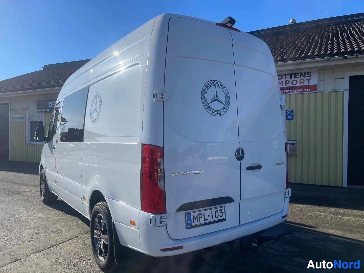 Takaviisto: Valkoinen Mercedes-Benz Sprinter takaosan kolmasosasta, rekisteritunnus, takavaijerikoulu kytketty.