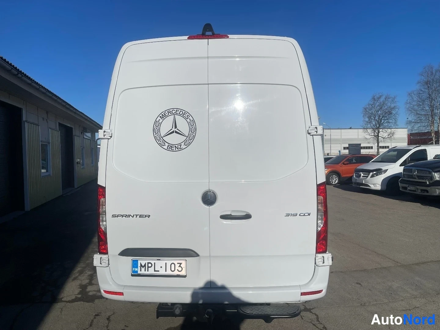 Takaa: Mercedes-Benz Sprinter suoraan takaa, valkoinen takaluukku, SPINTER ja 319 CDI -tekstit, rekisterikilpi.