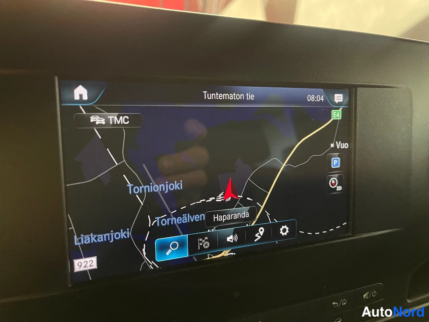 Muu: Infotainment-näytön lähikuva: navigaatio näyttää tekstiä 'Tuntematon tie', paikkoja Haparanda, Tornionjoki ja Torneälven.