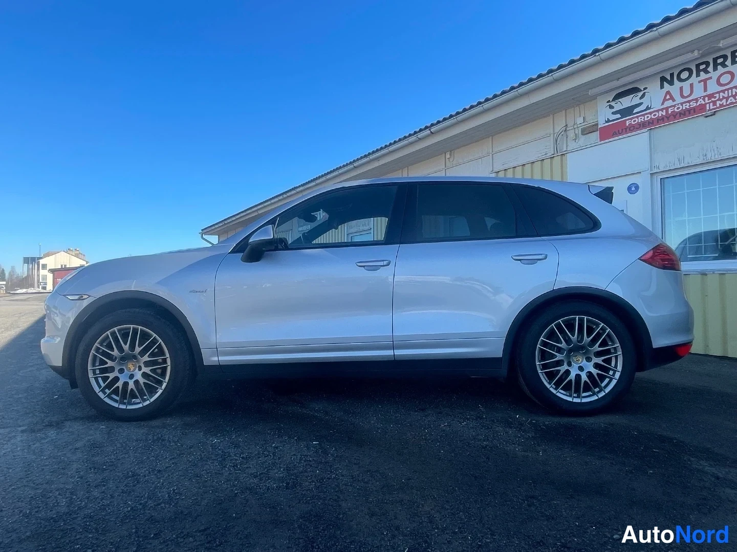 Sivulta: Hopeainen Porsche Cayenne kylkiäisestä vasemmalta, takaosan osa näkyy.