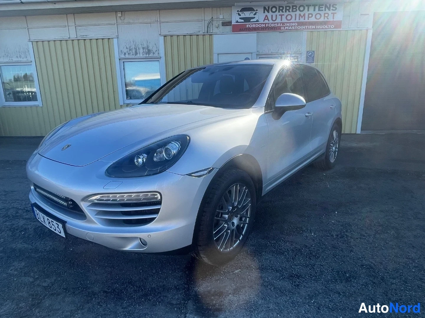Etuviisto, nokka vasemmalle: Porsche Cayenne -maasturi edestä vasemmalta kolmasosakulmasta valtiaspyörän edessä, hopeanvärisenä.