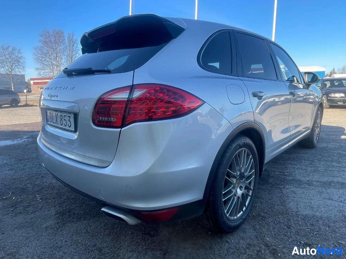 Takaviisto: Hopeanharmaa Porsche Cayenne takaa oikealta kuvattuna, takavalo ja kevytmetallivanteet näkyvissä.