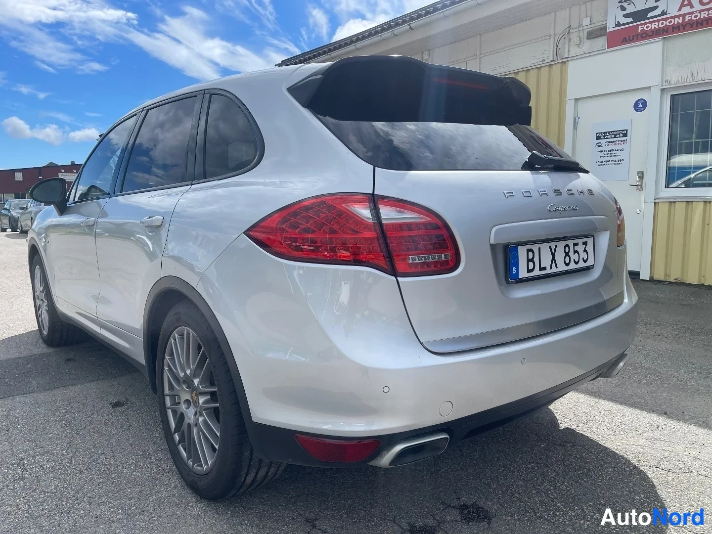 Takaviisto: Porsche Cayenne -maasturin takaosa ja vasen kylki kolmeneljäsosan takakuvassa; hopeakorisessa korissa näkyvät punaiset takavalot, PORSCHE Cayenne -tekstit ja ru