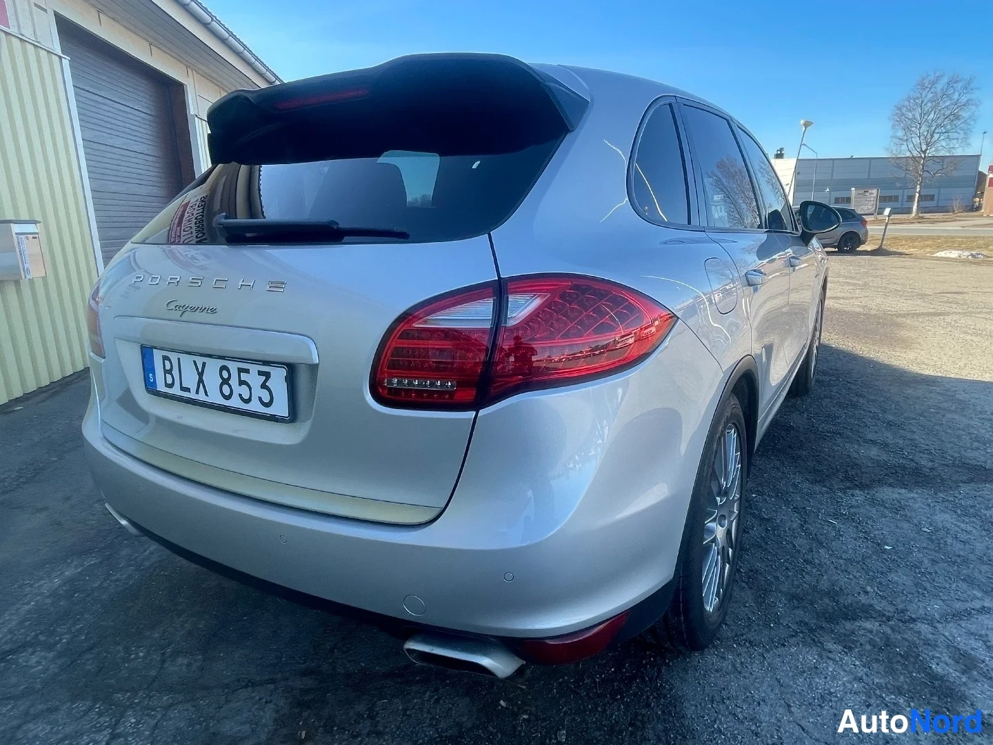 Takaviisto: Porsche Cayenne -maasturin takaosa ja oikea kylki kolmeneljäsosan takakuvassa; takaluukussa PORSCHE Cayenne -tekstit ja rekisterikilpi BLX 853, korin väri hopea