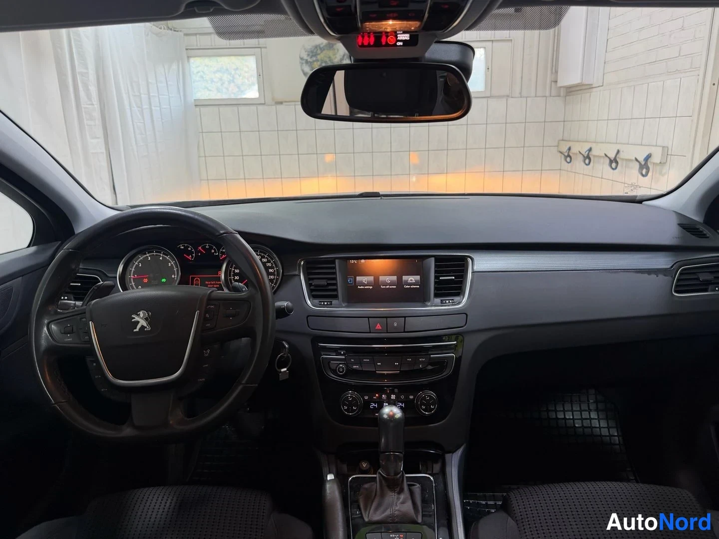Muu: Ohjaamo näkyvissä: Peugeot-ohjauspyörä, mittaristo ja keskikonsoli näytöineen.