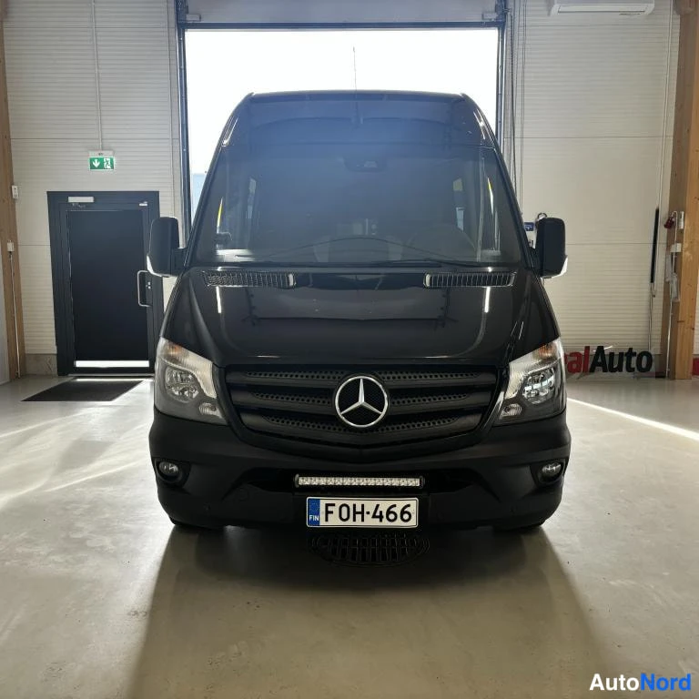 Edestä: Musta Mercedes-Benz Sprinter etusuoraan kuvattuna autotallissa, rekisterikilpi.