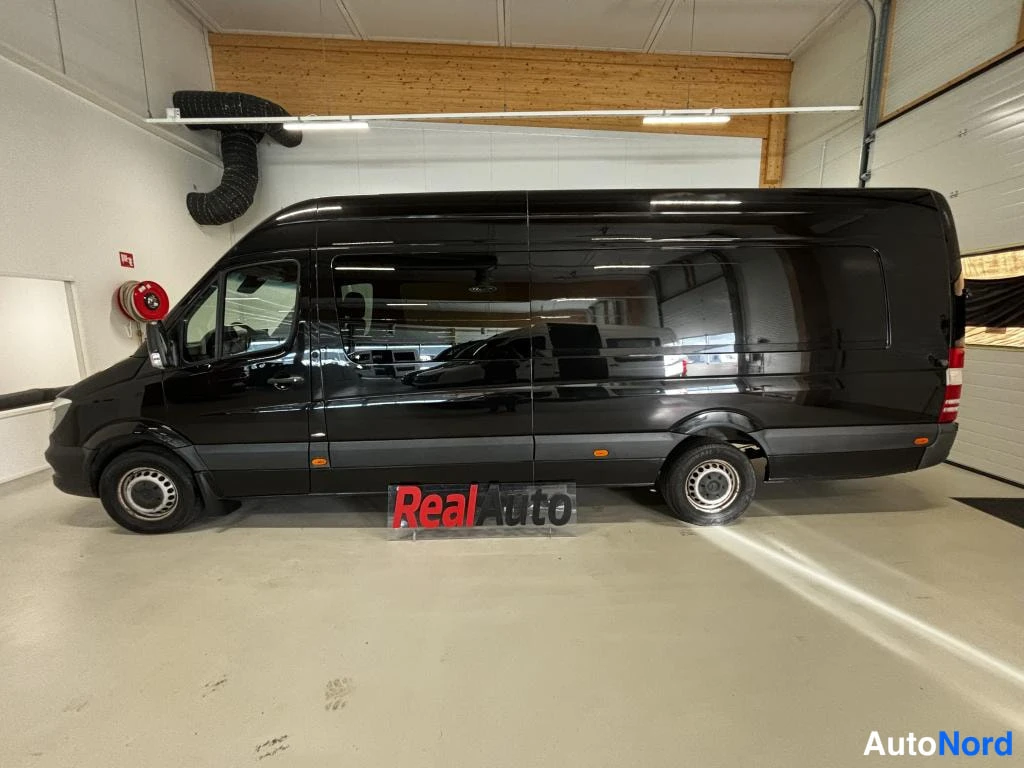 Etuviisto, nokka vasemmalle: Musta Mercedes-Benz Sprinter -pakettiauto sivusuunnasta kuvattuna autotallissa, koko ajoneuvo näkyvissä.