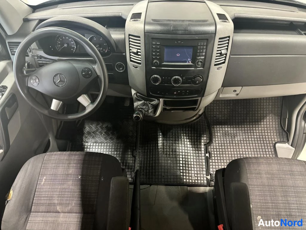 Muu: Mercedes-Benz Sprinter -tavaratilan sisäkuva ohjaamosta, tummat penkit ja manuaalivaihteisto
