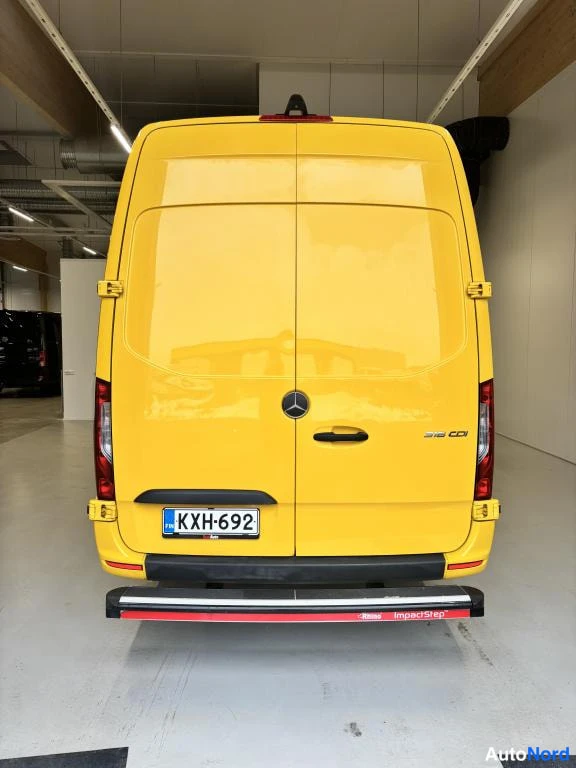 Takaa: Keltainen pakettiauto suoraan takaa; rekisterikilpi, musta puskuri ja merkki näkyvissä.