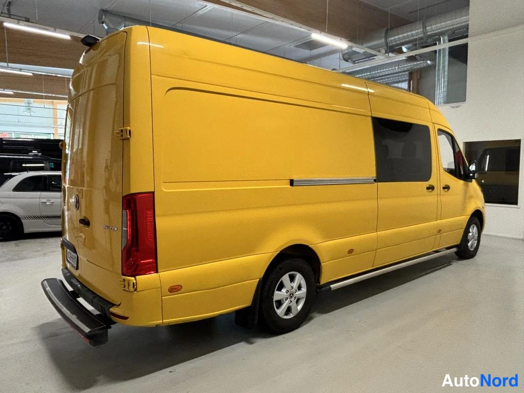Takaviisto: Keltainen pakettiauto takaa viistosta oikealta kuvattuna hallissa; oikea kylki ja takaosa näkyvissä.