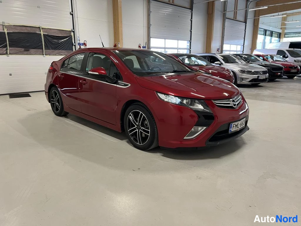 Etuviisto, nokka oikealle: Punainen Opel Ampera -henkilöauto etuviistosta hallissa, etusäleikkö auton oikeassa reunassa