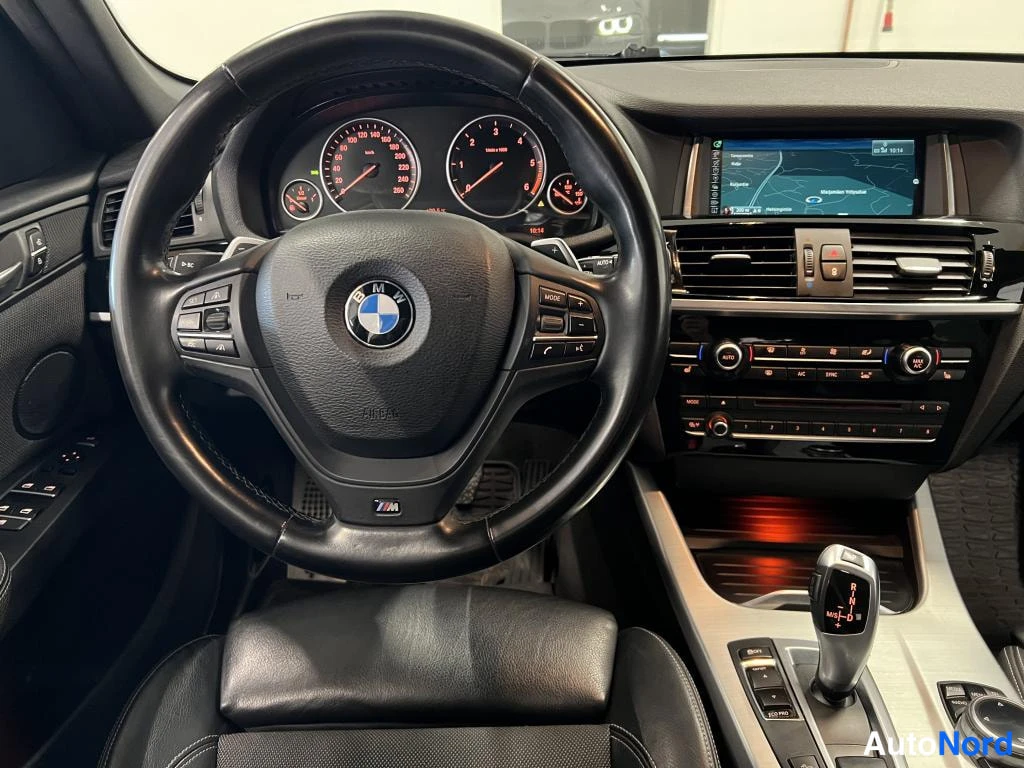 Muu: Kojelauta suoraan edestä: BMW-ohjauspyörä, mittaristo, karttanäyttö ja automaattivaihteen valitsin asennossa P.