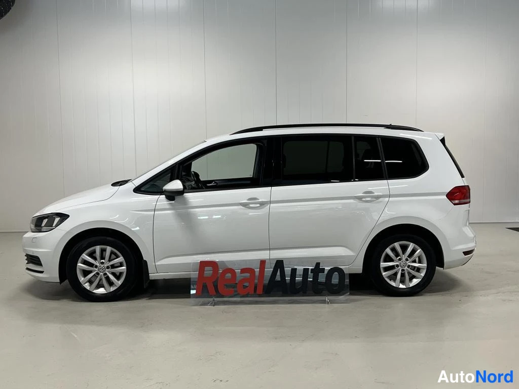 Sivulta: Valkoisen Volkswagen Touran -pakettiauton sivukuva sisätiloissa.