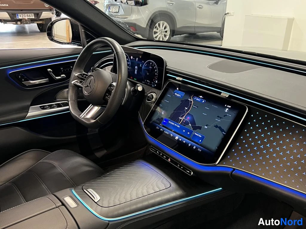 Sivulta: Kuljettajan puolen ohjaamo: Mercedes-ohjauspyörä, digitaalinen mittaristo, kartta näyttävä keskinäyttö ja sininen ympäristövalaistus. Mustat penkit ja keskikons