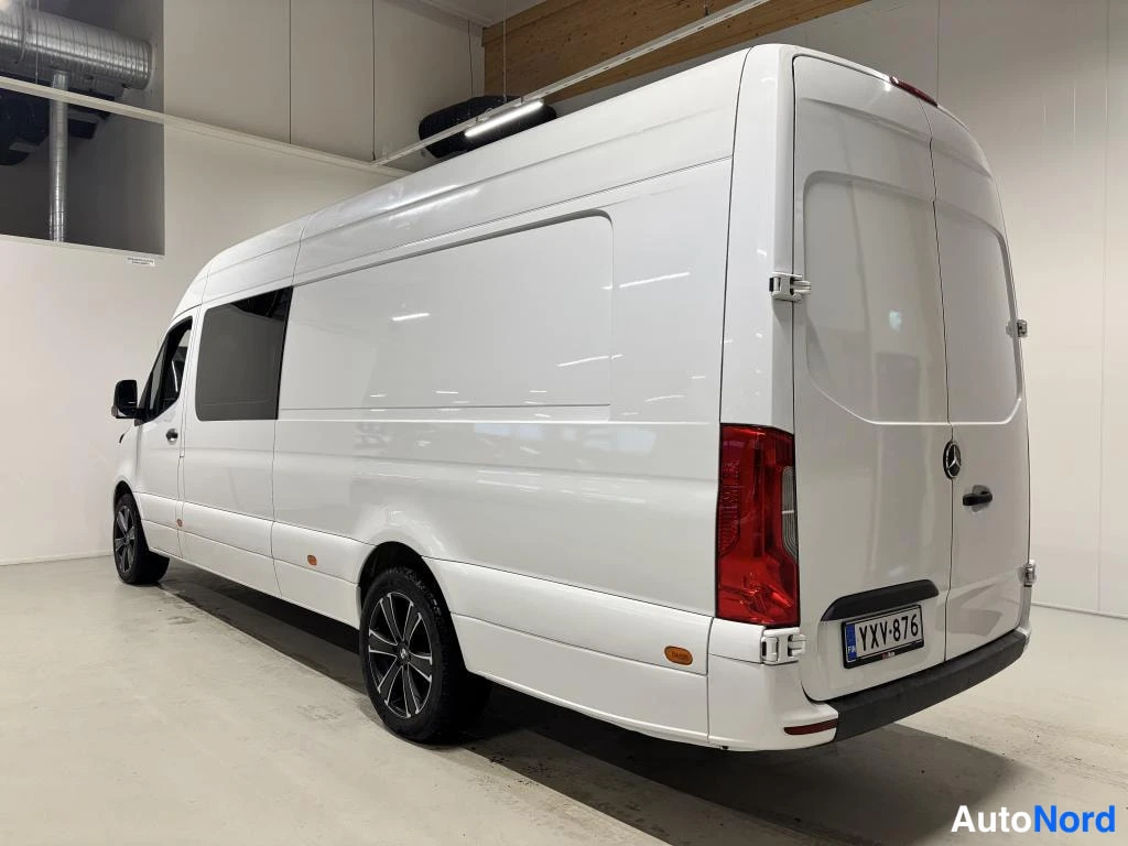 Takaviisto: Valkoinen Mercedes-Benz Sprinter -pakettiauto sivulta takaa päin kuvattuna; takana kaksoisovet, punaiset takavalot ja rekisteritunnus.