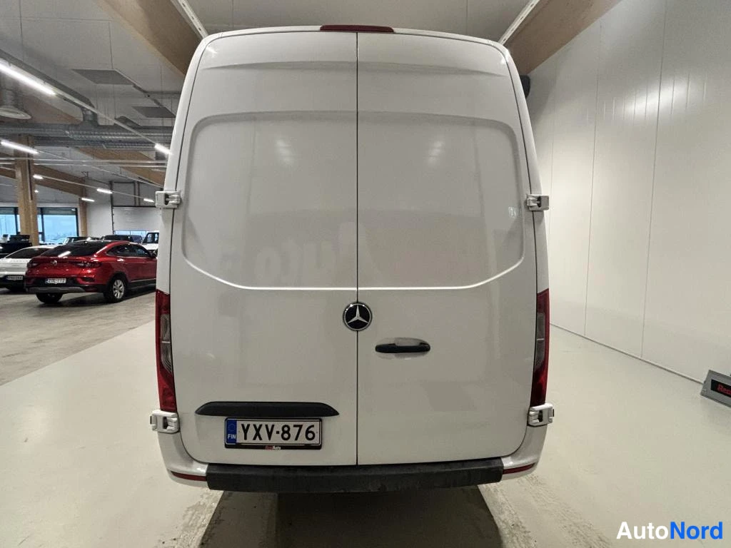 Takaa: Valkoisen Mercedes-Benz Sprinter -pakettiauton takaosa suoraan takaa kuvattuna; kaksoisovet, Mercedes-tähti ja rekisteritunnus.