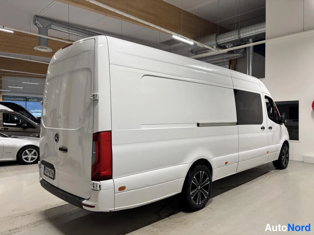 Takaviisto: Valkoinen Mercedes-Benz Sprinter -pakettiauto takaa ja vasemmalta sivulta kuvattuna; pitkä korirakenne, liukuoVI ja takana kaksoisovet.