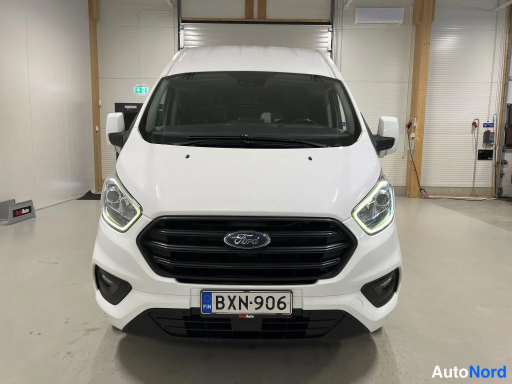 Edestä: Valkoinen pakettiauto edestäpäin, Ford-merkki säleikkössä ja rekisterikilpi.
