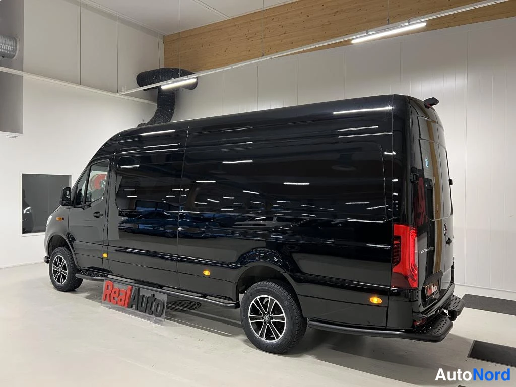 Takaviisto: Musta Mercedes-Benz Sprinter -pakettiauto takaviisto kuvattuna sisätiloissa, sivut ja takapää näkyvissä.