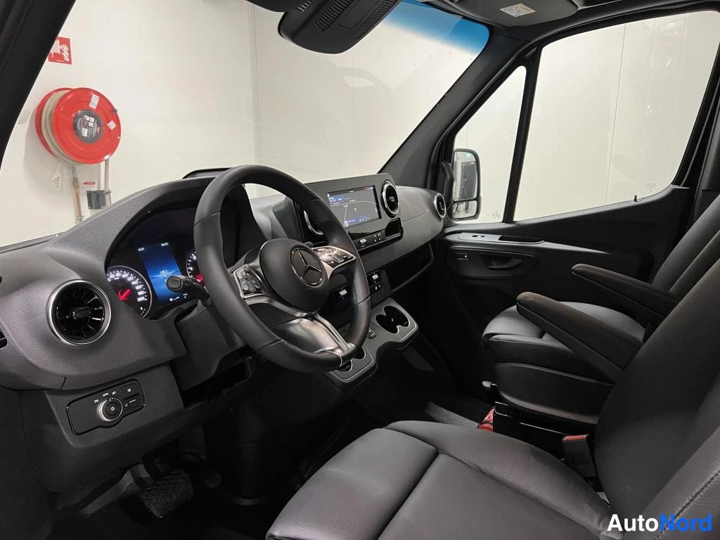 Muu: Sisätila Mercedes-Benz Sprinter -autosta: ohjauspyörä ja kojelaudan näyttö, tummat penkit