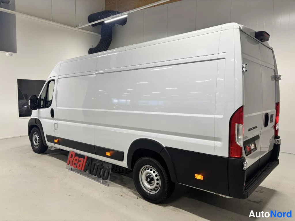 Takaviisto: Valkoinen pakettiauto takaviistosta sisätiloissa, DUCATO-teksti takakannessa.
