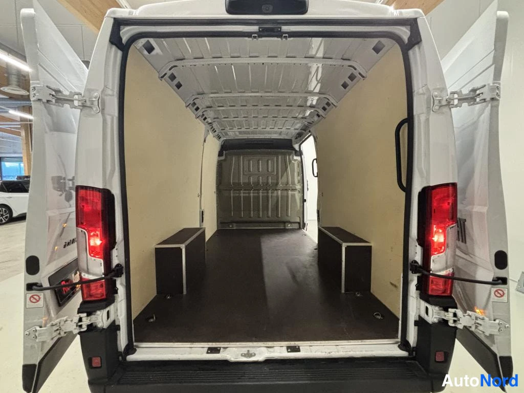 Takaa: Fiat Ducato -pakettiauton tavaratila avattujen takaporttien läpi, vaaleat seinäpaneelit ja tumma lattia.