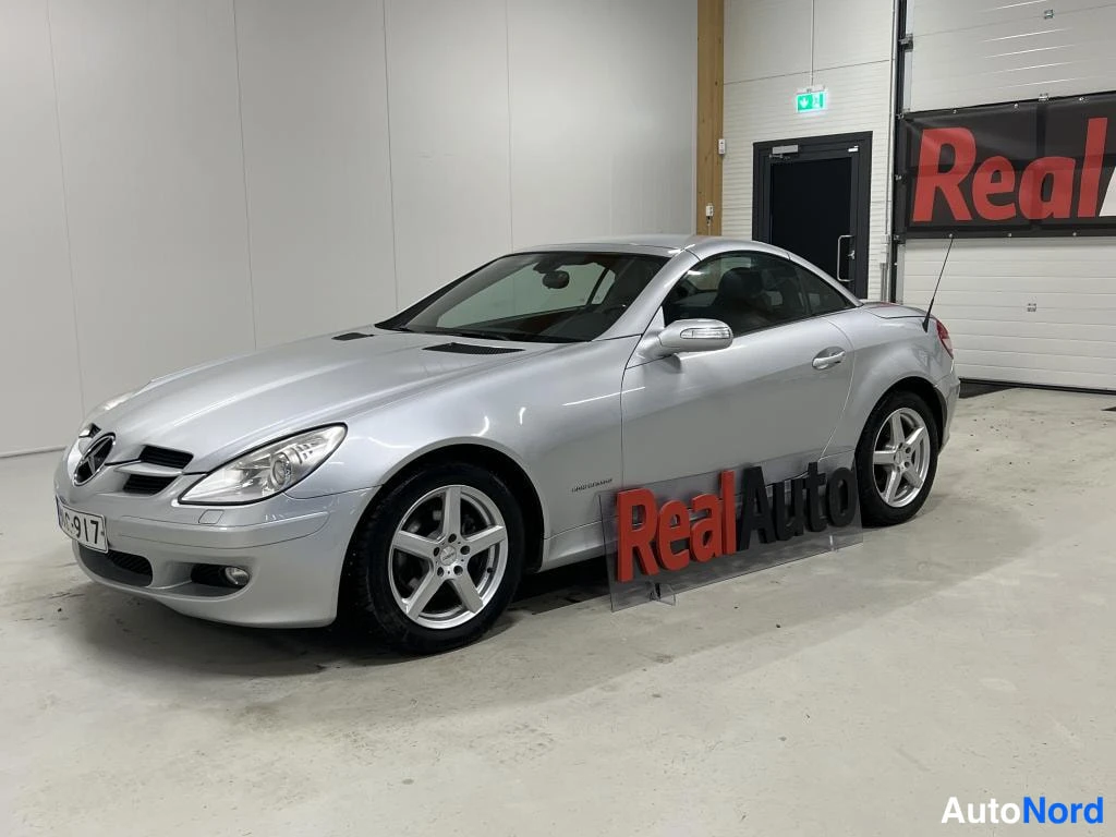 Etuviisto, nokka vasemmalle: Mercedes-Benz SLK kovakatto kiinni, hopeinen, etuosa vasemmalla kulmasta, hopeavanteet.