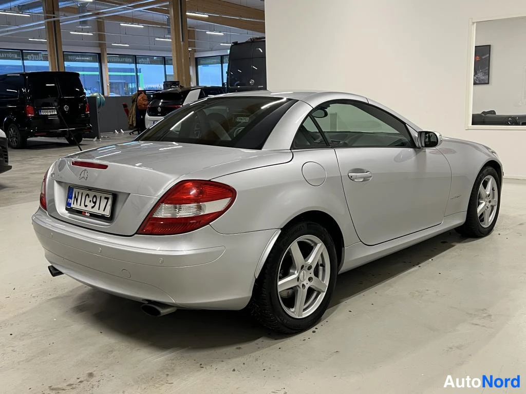 Takaviisto: Auton takaosa vasemmalta kolmessa neljänneksessä: hopea Mercedes-Benz SLK, rekisterikilpi.