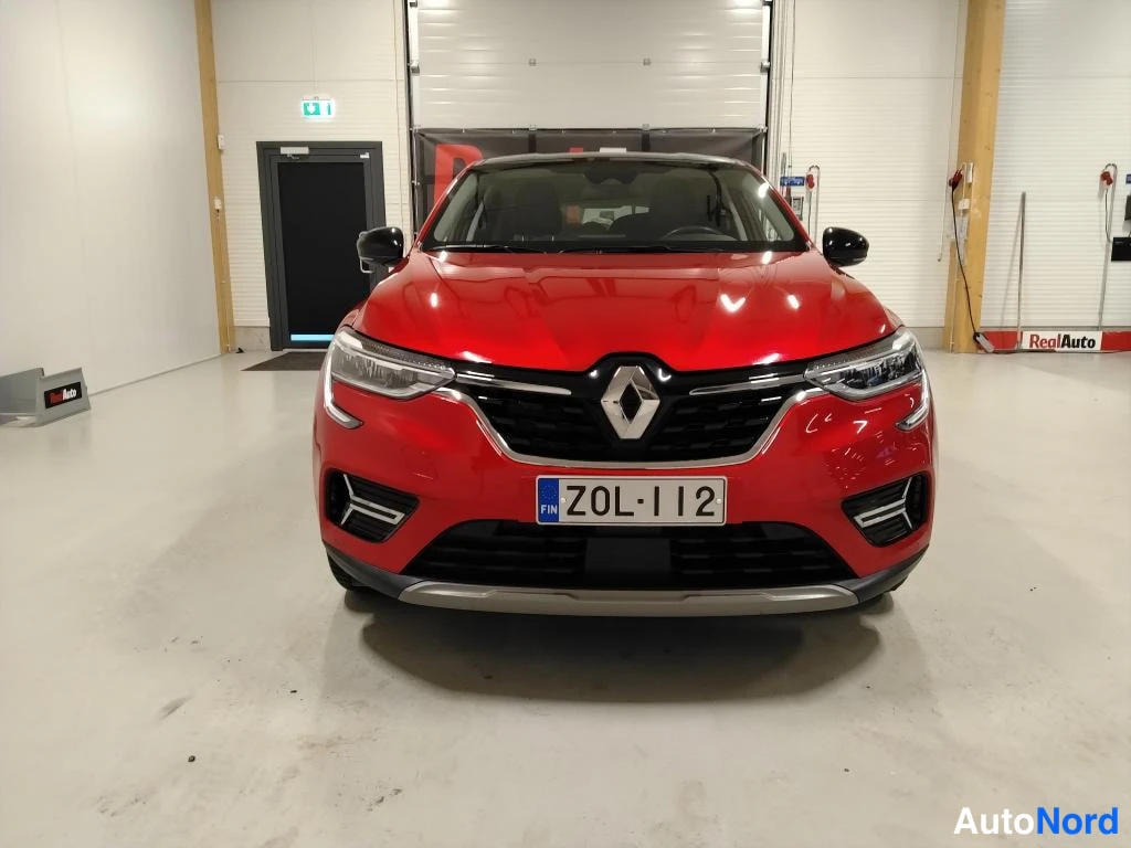 Edestä: Punainen auto suoraan edestäpäin, etusäleikkö ja ajovalot näkyvät, rekisterikilpi.