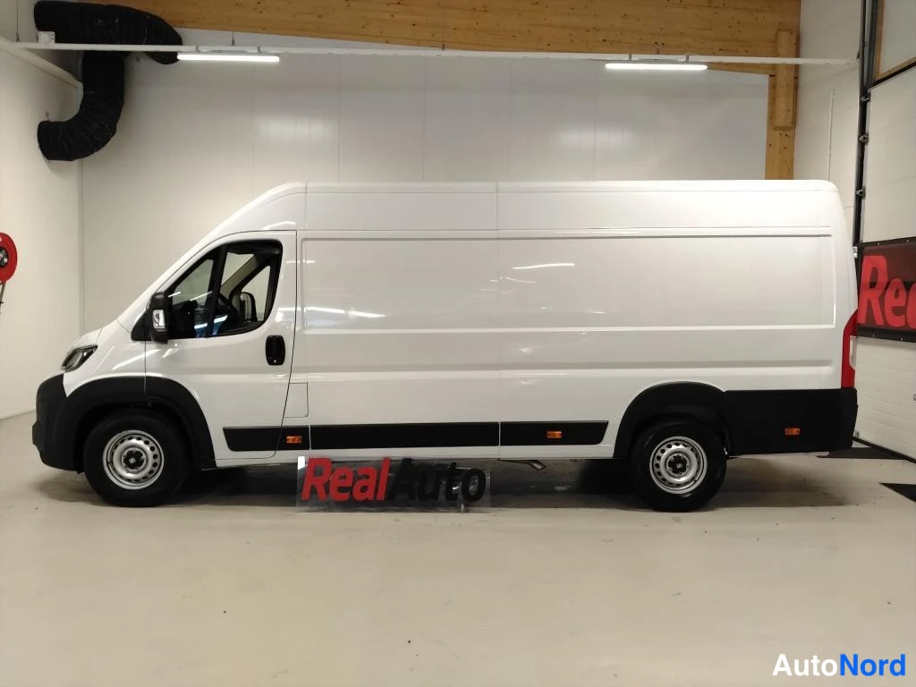 Sivulta: Fiat Ducato -pakettiauto suoraan sivulta valkoisena sisätiloissa.