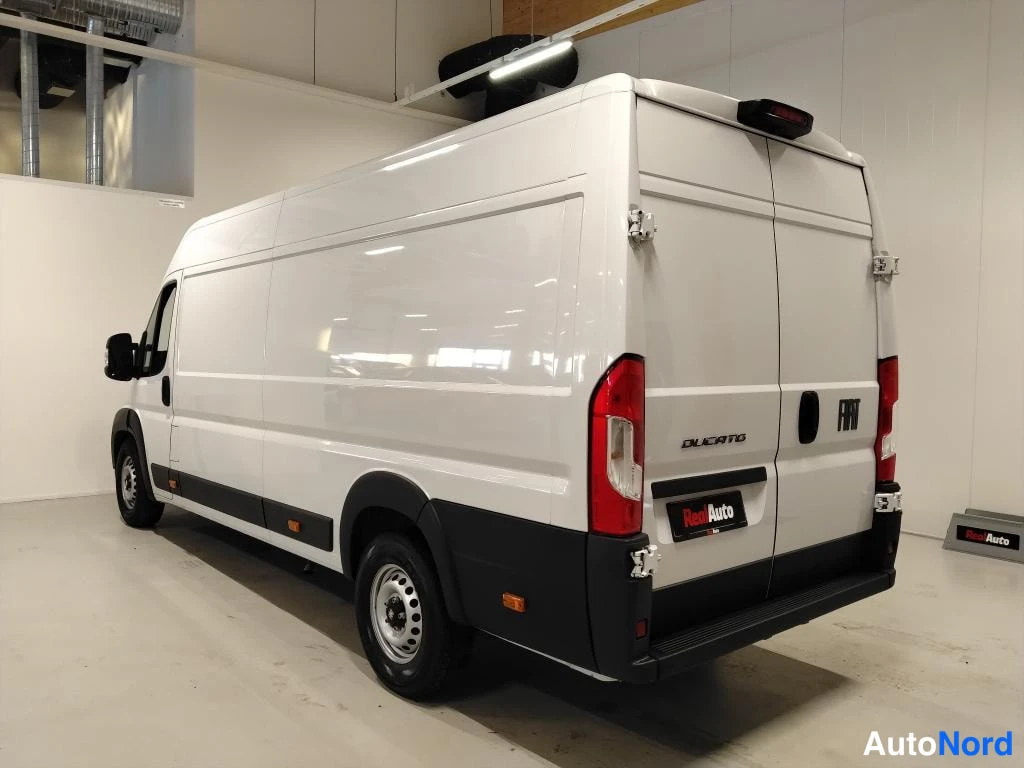 Takaviisto: Fiat Ducato -pakettiauto takaa viistosta oikealta; valkoinen koripaneeli, takana Ducato- ja Fiat-merkit, punaiset takavalot.
