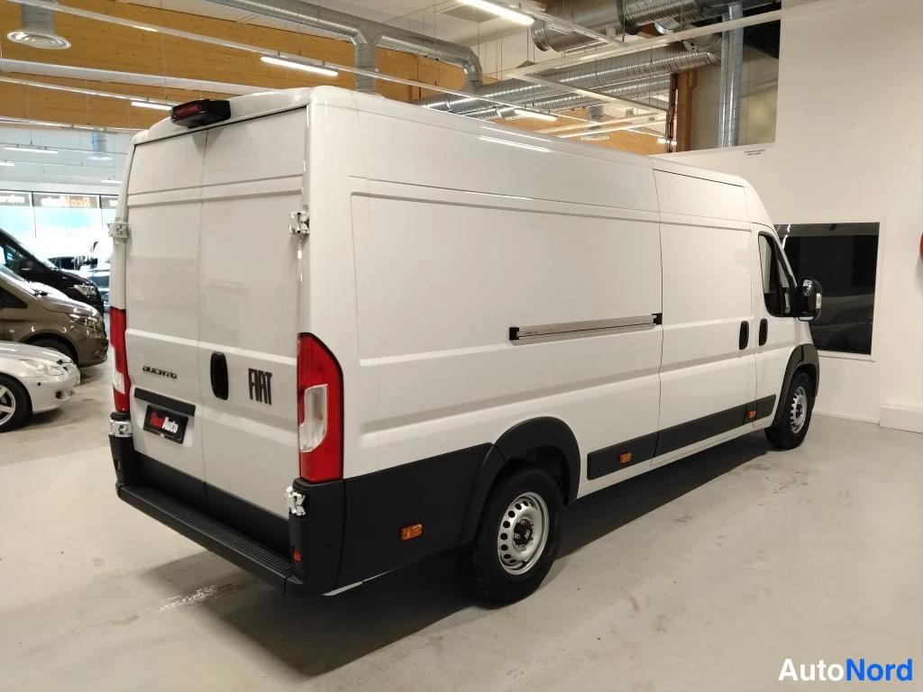 Takaviisto: Fiat Ducato -pakettiauto takaa viistosta vasemmalta; valkoinen pitkä koripaneeli, takana Fiat-merkki, mustat puskurit ja alustan osat.