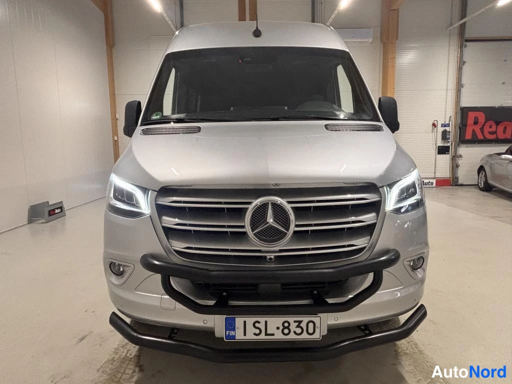 Edestä: Etukuvassa hopeinen Mercedes-Benz Sprinter -pakettiauto, rekisterikilpi ja musta puskurikaari näkyvissä.