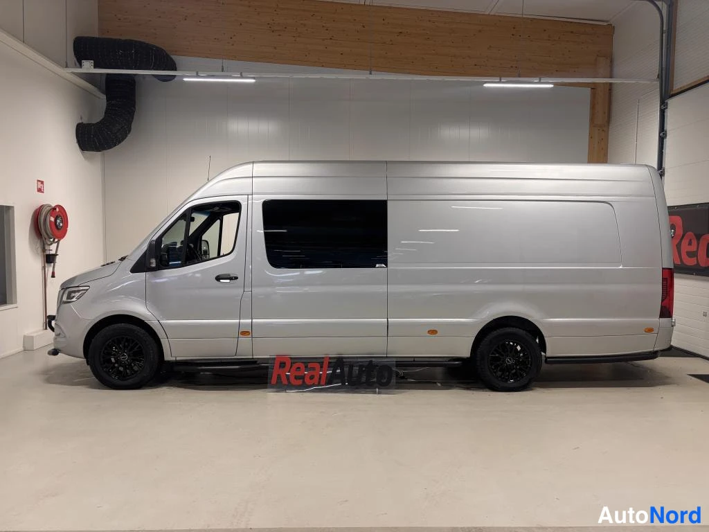 Sivulta: Sivukuva hopeisesta Mercedes-Benz Sprinter -pakettiautosta hallissa, tummat ikkunat ja mustat kevytmetallivanteet.
