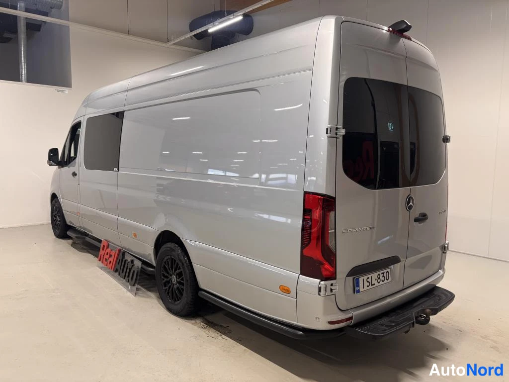 Takaviisto: Hopeaharmaa Mercedes-Benz Sprinter -pakettiauto takaviistosta kuvattuna sisätiloissa; rekisterikilpi SL-830 ja vetokoukku näkyvät.