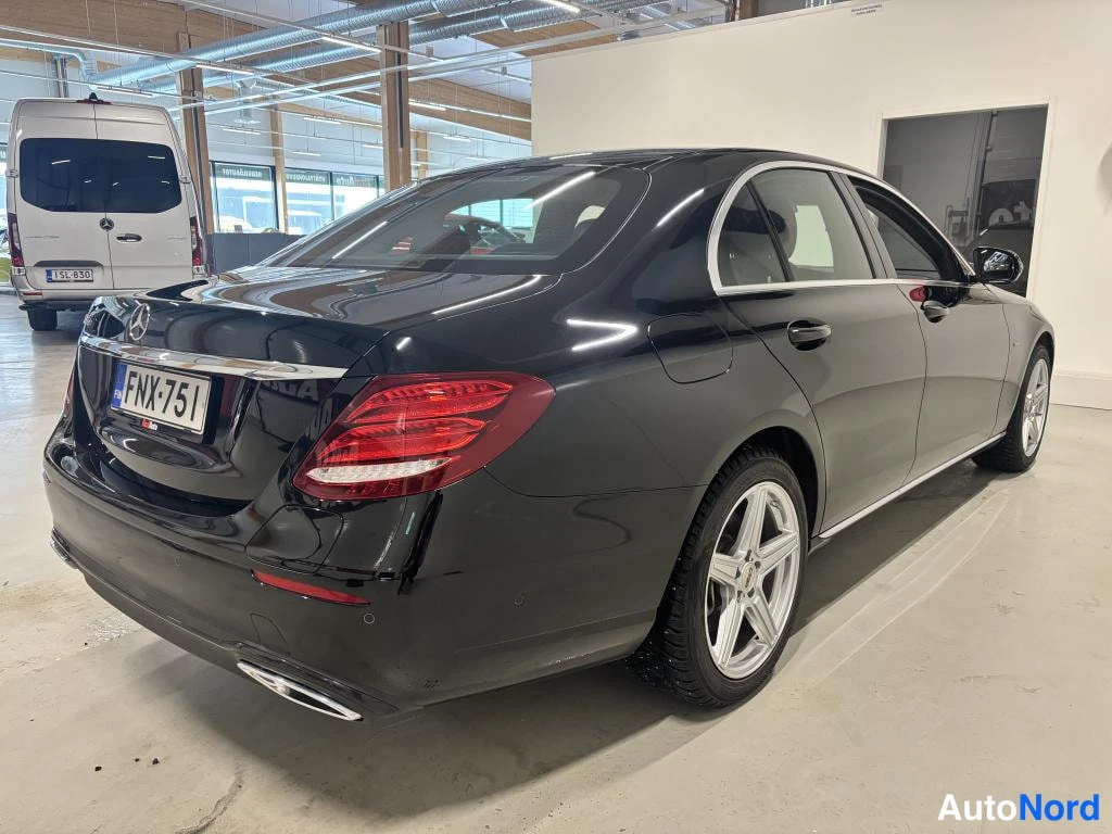 Takaviisto: Mustan Mercedes-Benzin takaosa ja sivu kolmesivukulmassa oikealta, rekisterikilpi.