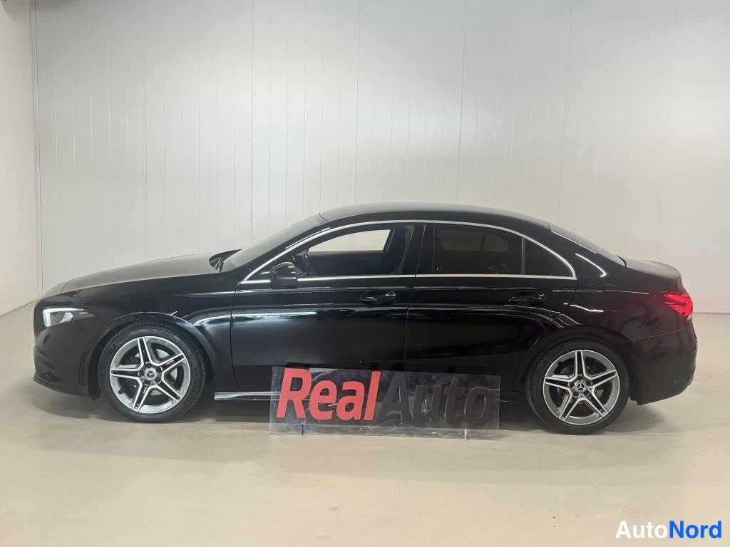 Sivulta: Mustan Mercedes-Benz A -sedanin sivunäkymä vasemmalta, auto suoraan sivusta sisätiloissa.
