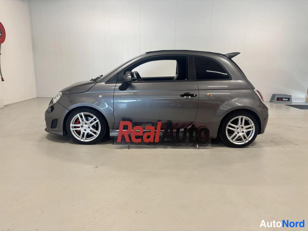 Sivulta: Sivunäkymä harmaasta Fiat 500 Abarthista vasemmalta sisätilassa, kevytmetallivanteet ja punaiset jarrusatulat.