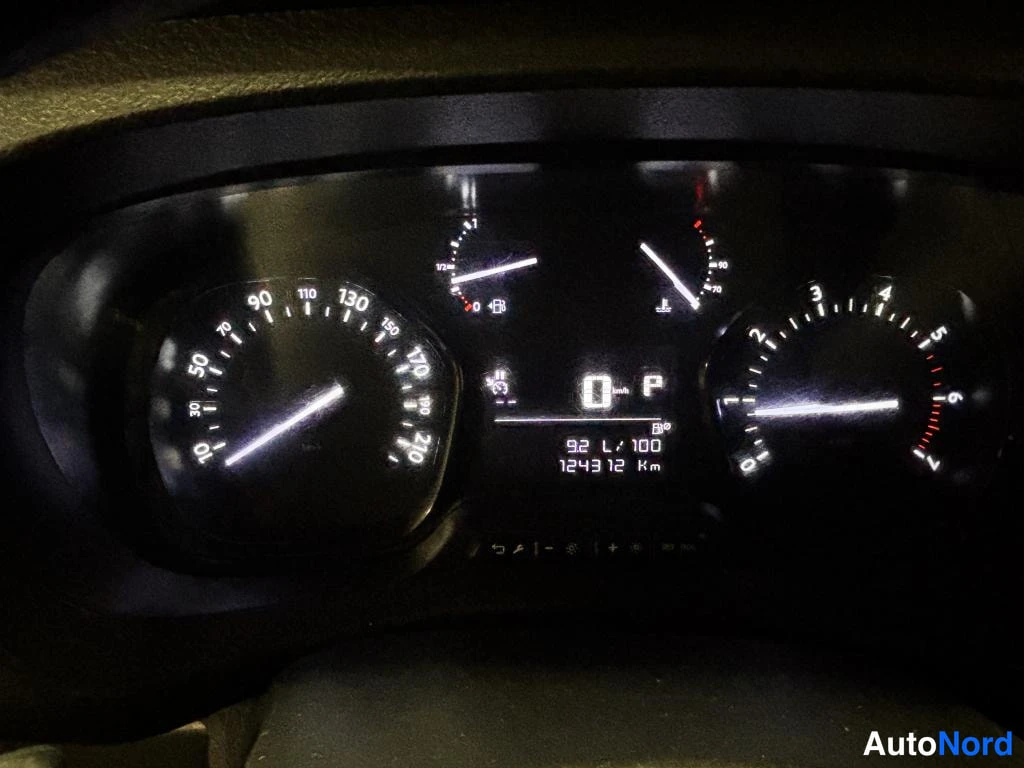 Muu: Auton kojelauta pimeässä: nopeusmittari, kierroslukumittari, polttoaine- ja lämpömittarit valaistuina. Keskellä näyttö ilmoittaa 0 km/h, vaihteen P, 92 L/100 ja