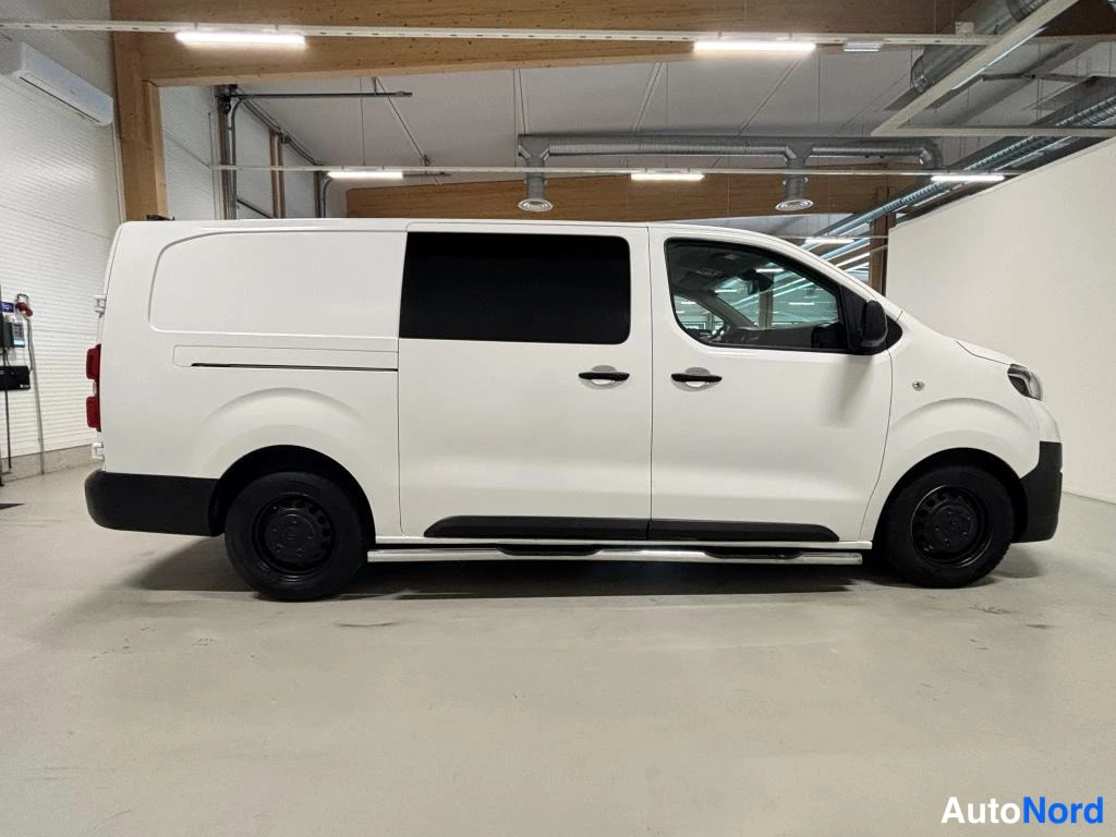 Sivulta: Valkoinen pakettiauto sivulta kuvattuna sisätilassa.