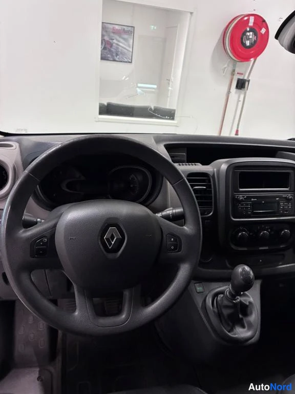 Muu: Kuljettajan näkökulma ohjauspyörään Renault-logolla, kojelauta ja radio keskikonsolissa, manuaalivaihteenkeksi oikealla.