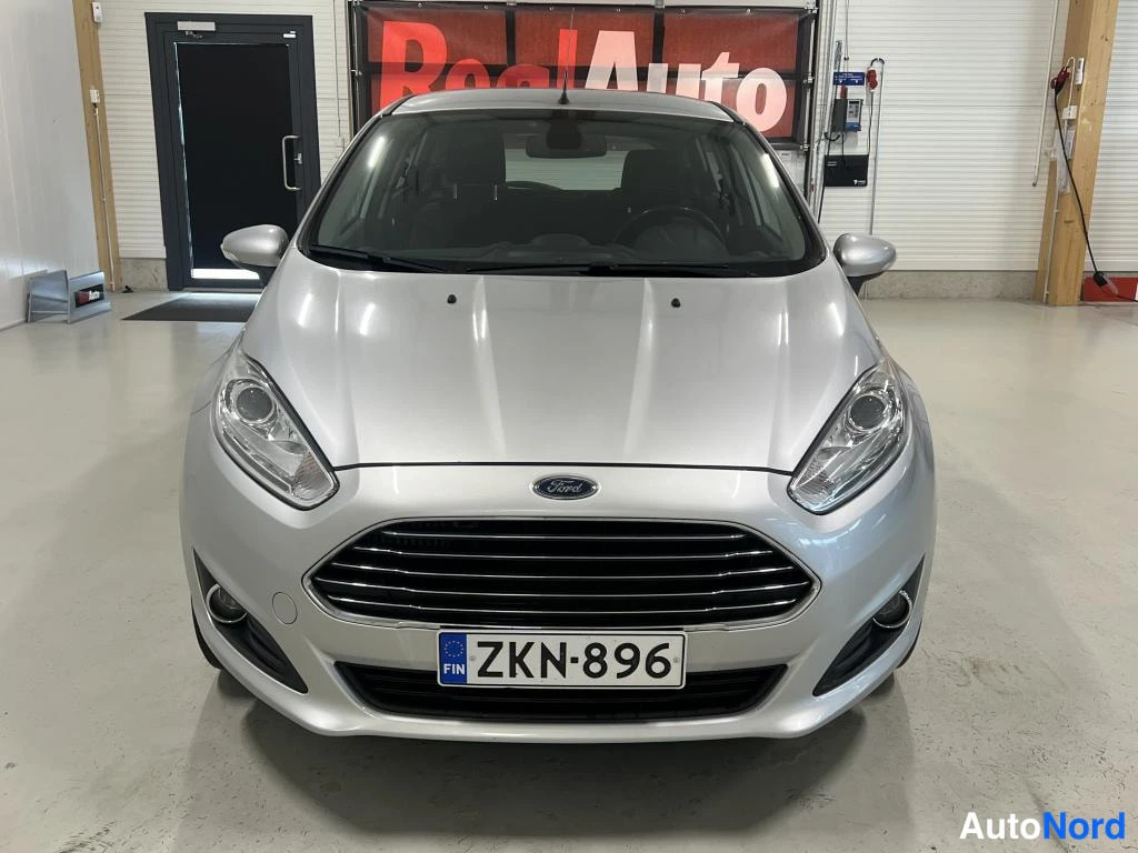 Edestä: Ford Fiesta -auton etunäkymä suoraan edestä kuvattuna sisätiloissa, rekisterikilpi