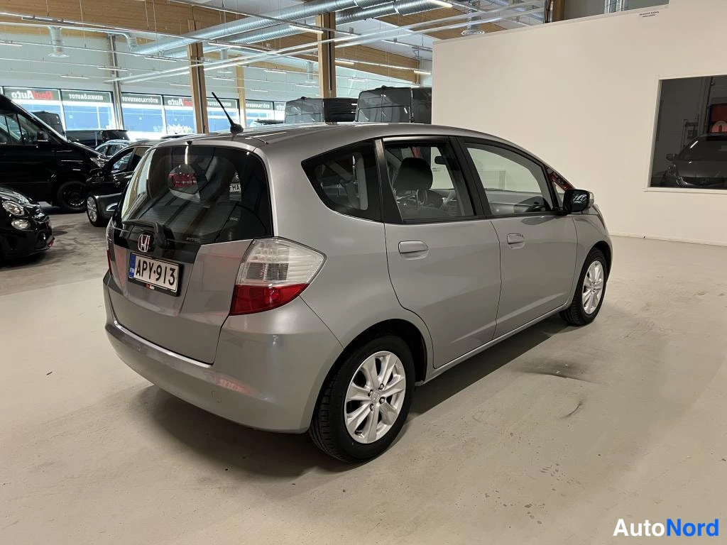 Takaviisto: Hopeanvärä viisiovinen tila-auto takaa-sivulta, rekisterikilpi.