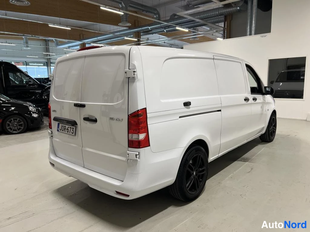 Takaviisto: Valkoinen pakettiauto kuvattu takaviistosta sisätiloissa; takaovet, kylki ja takapyörä näkyvät.