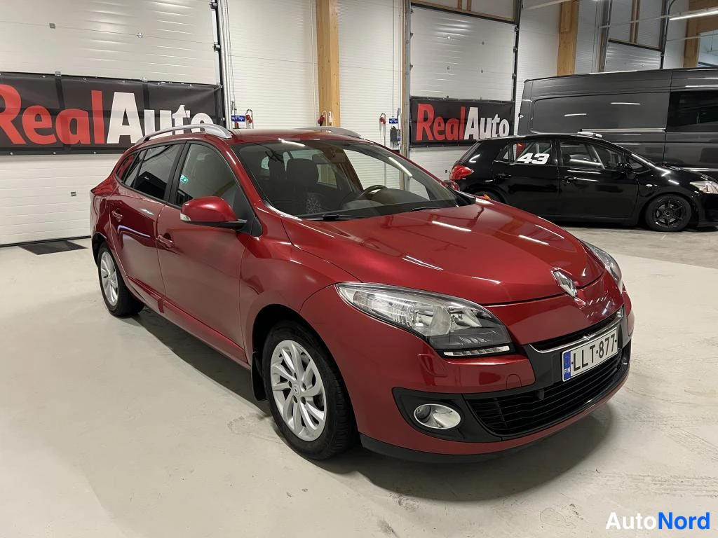 Etuviisto, nokka oikealle: Punaisen Renault Meganen etuosan sivukulma; etusäleikkö, ajovalot ja rekisteritunnus näkyvät.