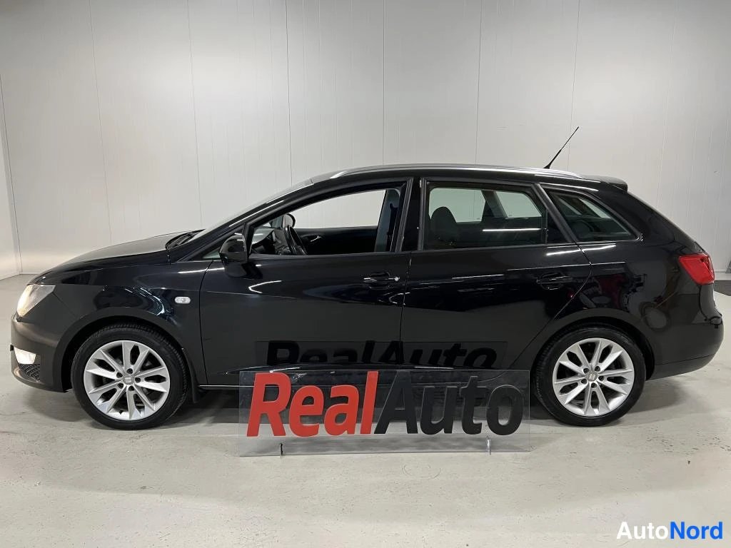 Sivulta: Musta Seat Ibiza ST farmari sivulta oikealta kuvattuna, koko korisivu ja molemmat pyörärivit näkyvissä, hopeat kevytmetallivanteet.