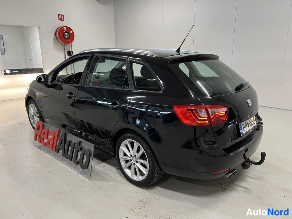 Takaviisto: Musta Seat Ibiza ST farmari takakulmasta vasemmalta, perä ja kylki näkyvissä, takavalot punaiset, rekisterikilpi, peräosassa vetokoukku ja kaksoispakoputki.