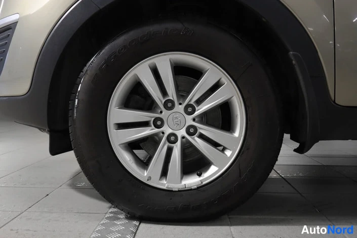 Muu: Lähikuva auton pyörästä: hopeinen viisipuolainen valetankovanne ja musta Goodyear-renkaat.