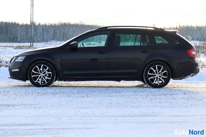 Sivulta: Sivukuvat mustasta farmariautosta lumisella pihalla.