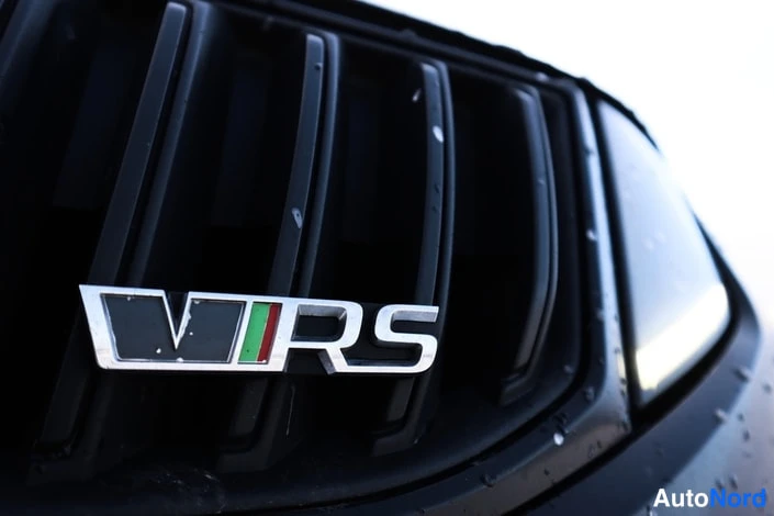 Yksityiskohta: Lähikuva auton etusäleiköstä, jossa on vRS-merkki, ja mustan korin pinnassa pisaroita.